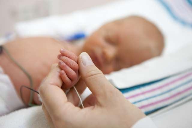 Baby in the NICU holding on to mom's hand.